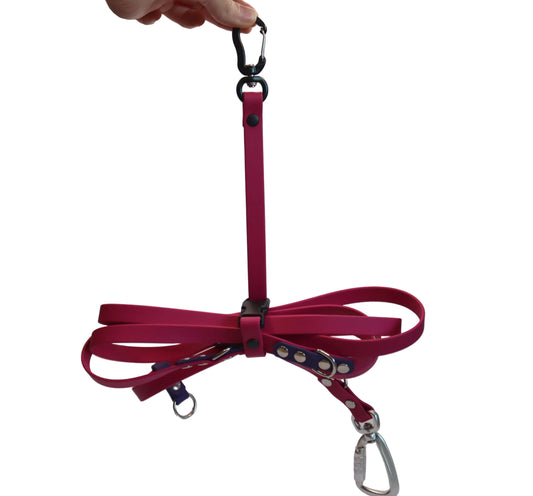 A magenta pink BioThane Long Line Keeper from DoggoZ holding a neatly folded long dog leash. The keeper features a black carabiner hook at the top for easy attachment to a bag or belt, and a secure buckle to keep the lead tangle-free.