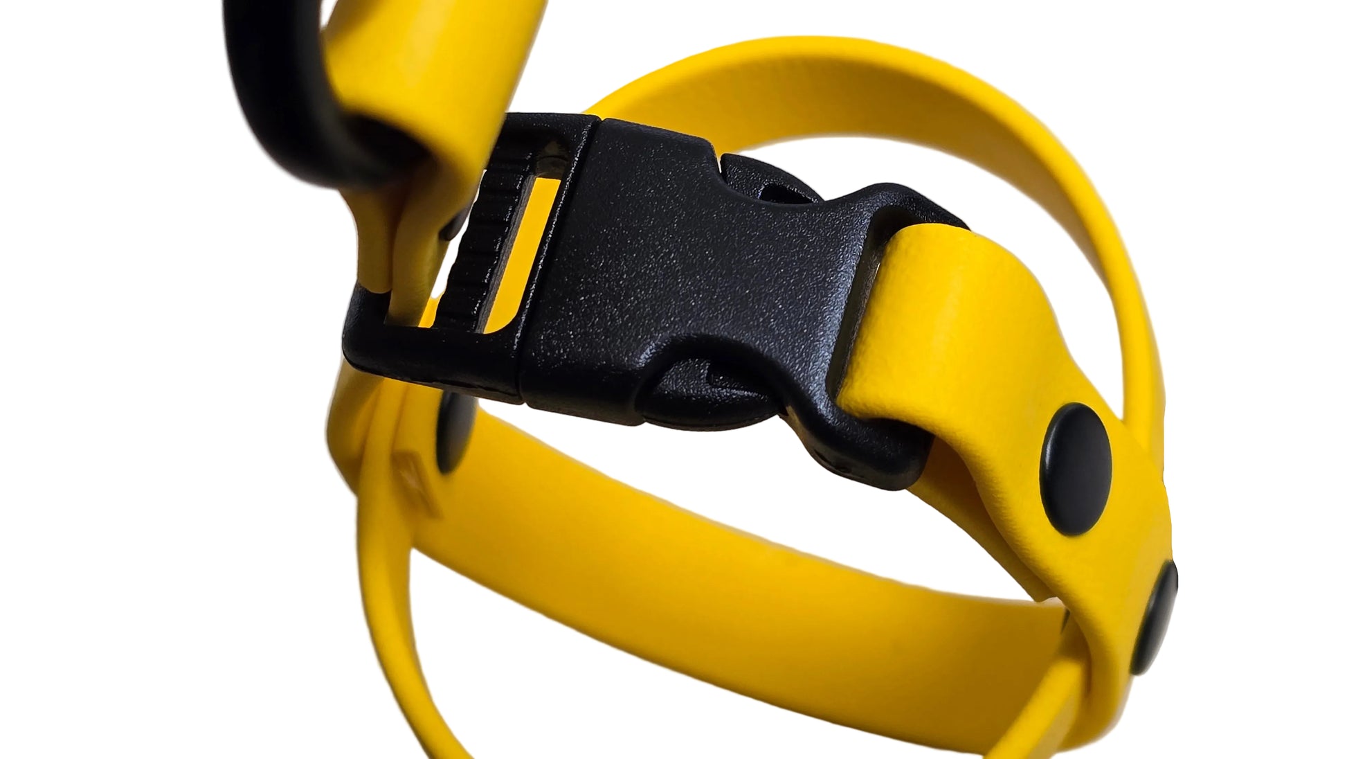 A macro close-up shot of the high-quality black plastic quick-release buckle on a yellow BioThane ball holder. The image highlights the durable buckle mechanism and the secure black rivets used to fasten the waterproof BioThane straps. This design allows for fast and easy access to your dog's favorite fetch ball during walks.